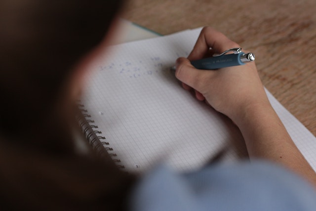 A Jack and Jill student writing mathematics in a notebook